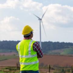 worker in high vis clothes looking at solar windmills